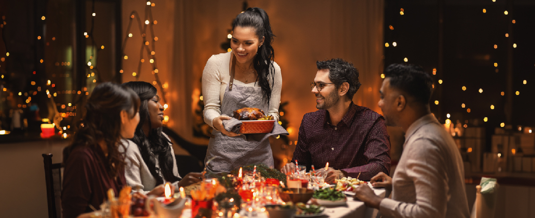 friend group gathered around the dinner table with festive lights in the background