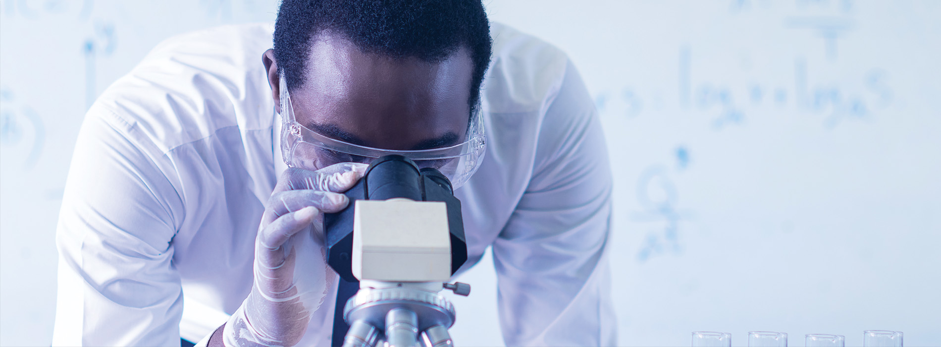 African male scientist looking in microscope in laboratory