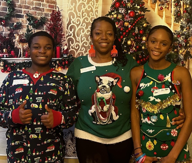 image of black family wearing festive holiday clothing smiling in front of decorated background