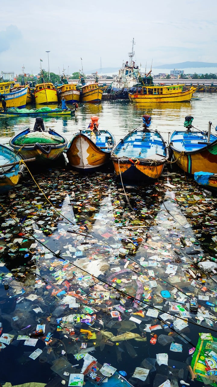 trash in the water by small boats