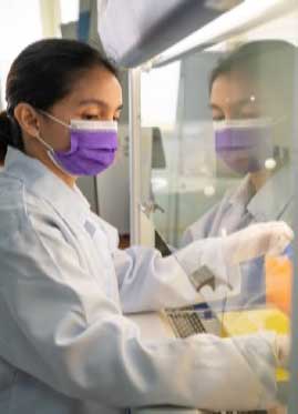 A scientist conducts an experiment behind glass.