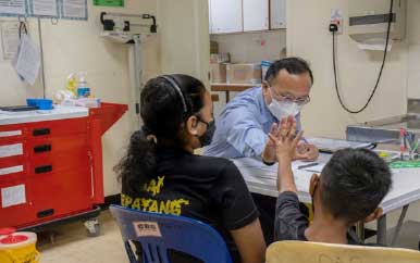 Dr. Toh high fives a male teen while sitting next to a young woman.