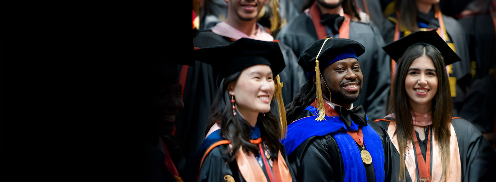 3 Students wearing graduation caps and gowns