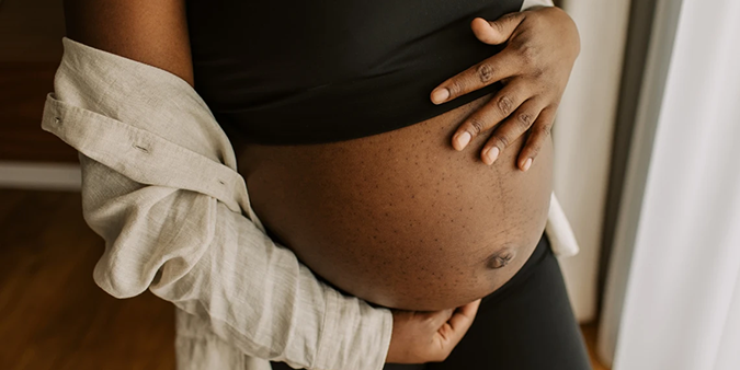 A visibly pregnant woman places her hands on her belly