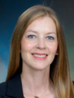 Chelsea Hoover A woman with long hair wearing a dark blazer against a blue gradient background is pictured in a professional head-and-shoulders portrait